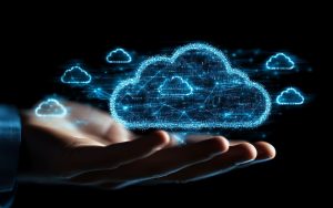 Main tenant une représentation numérique de nuages symbolisant le concept de multicloud, avec des connections lumineuses bleues sur fond sombre.